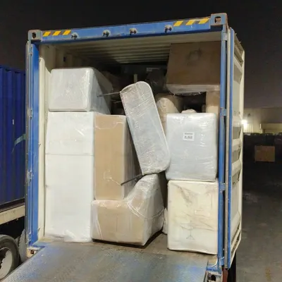 A container being loaded with wrapped household cargo at night